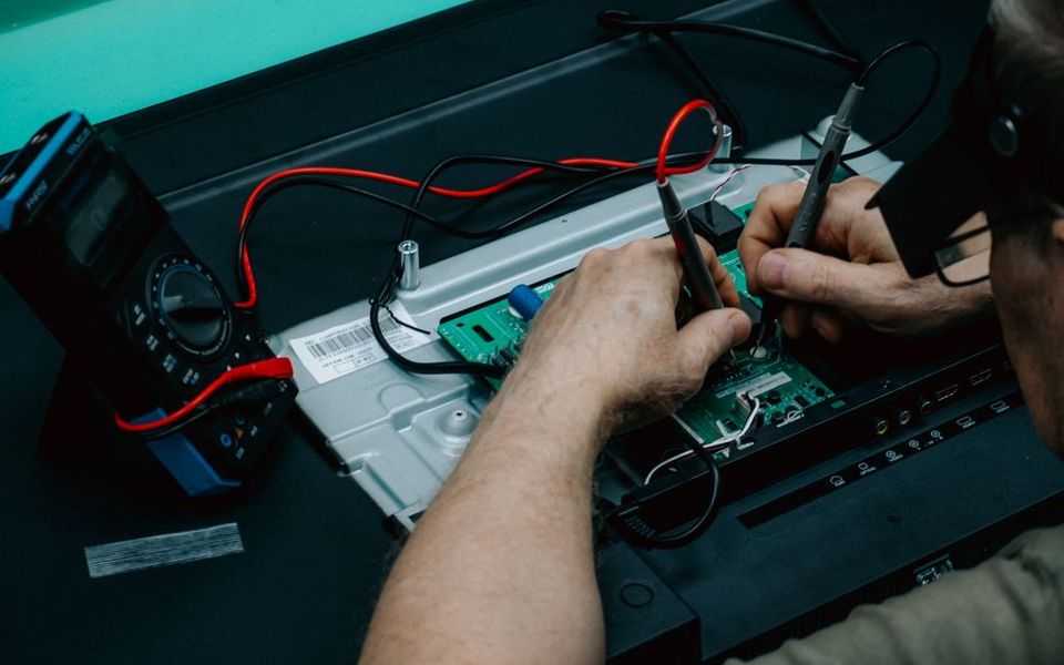 Technician testing a circuit board with a multimeter