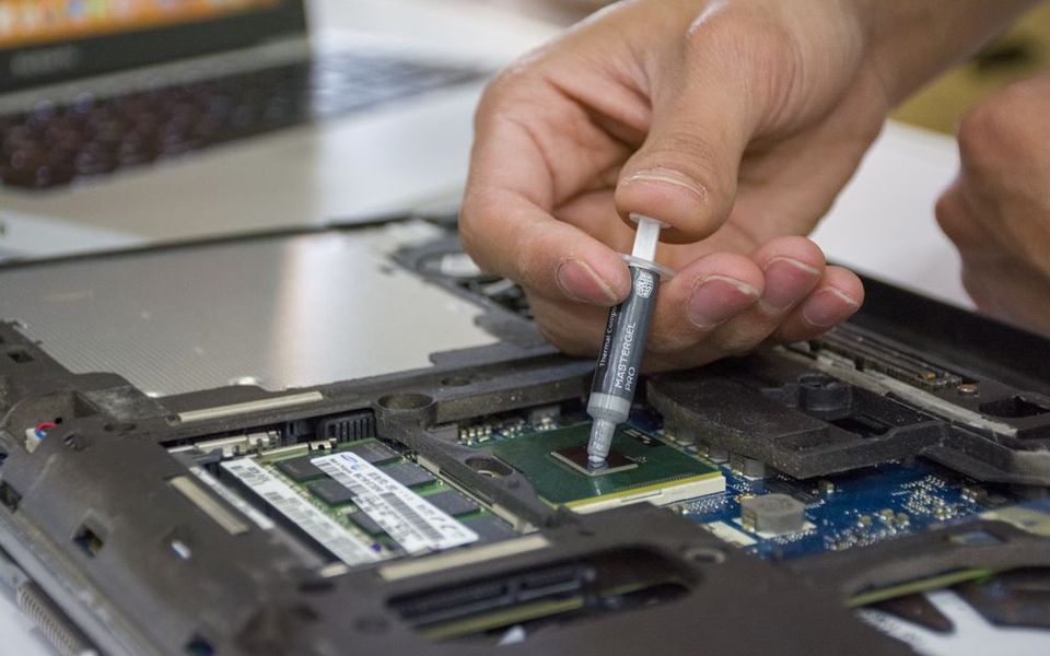 Technician applying thermal paste inside a laptop